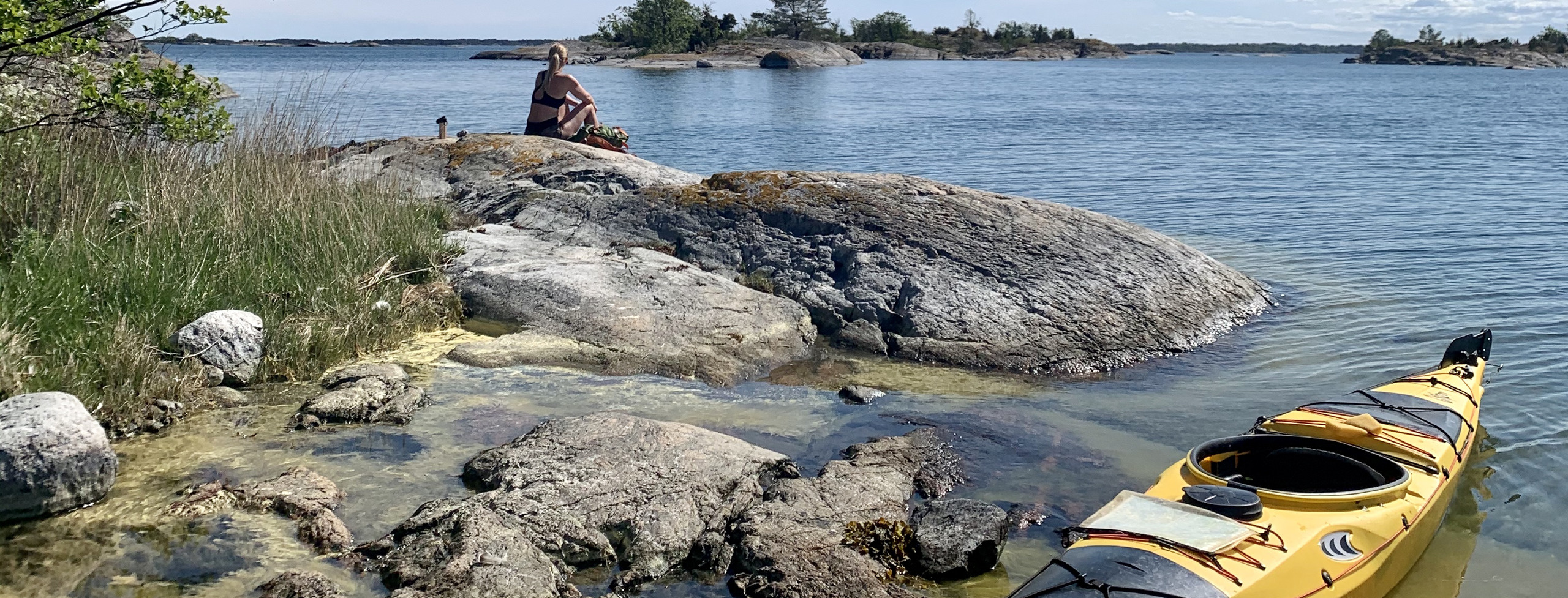 Bilden visar en gul kajak vid strandkanten på ön i Sankt Anna skärgård