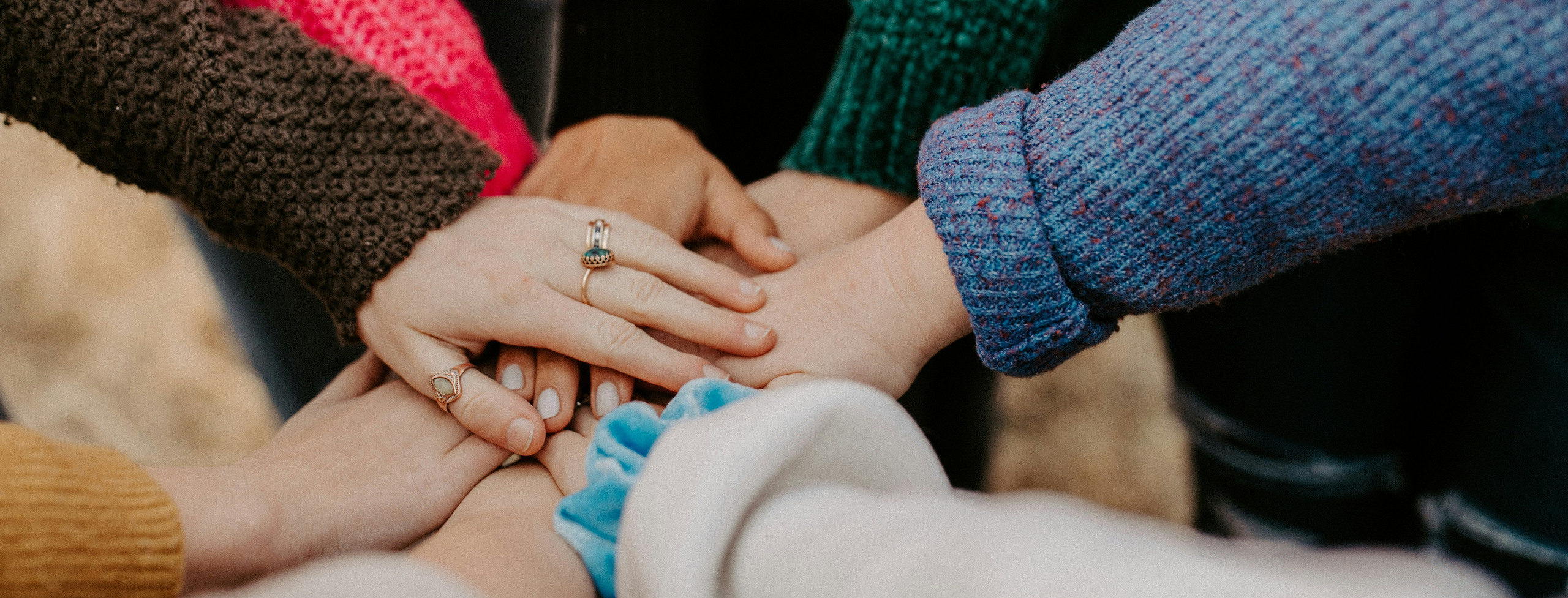 Händer i olika färger som sträcker sig in mot mitten