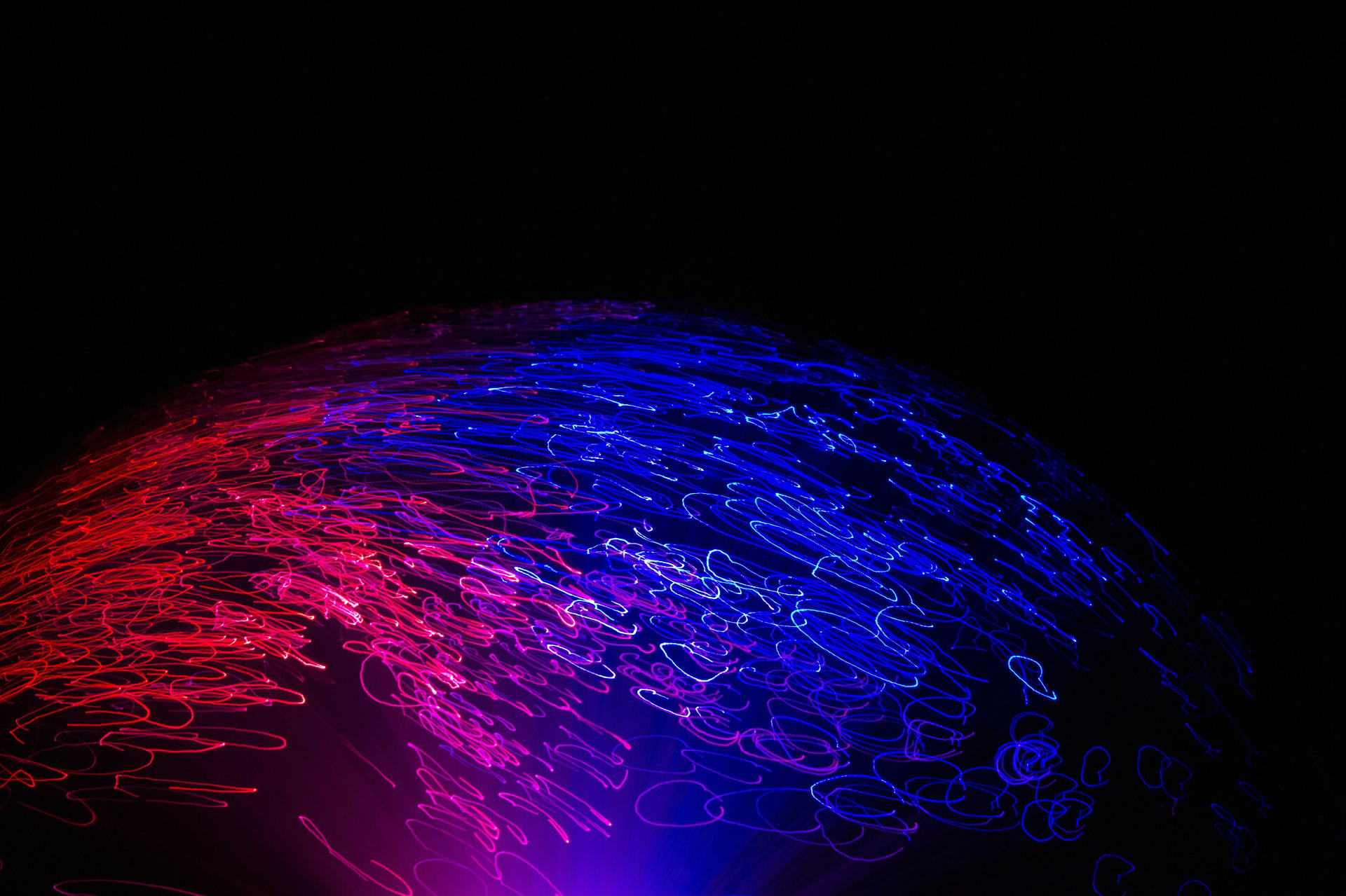 Bilden visar en m&ouml;rk bakgrund med ett f&auml;rgglatt sken som kommer fr&aring;n botten av bilden