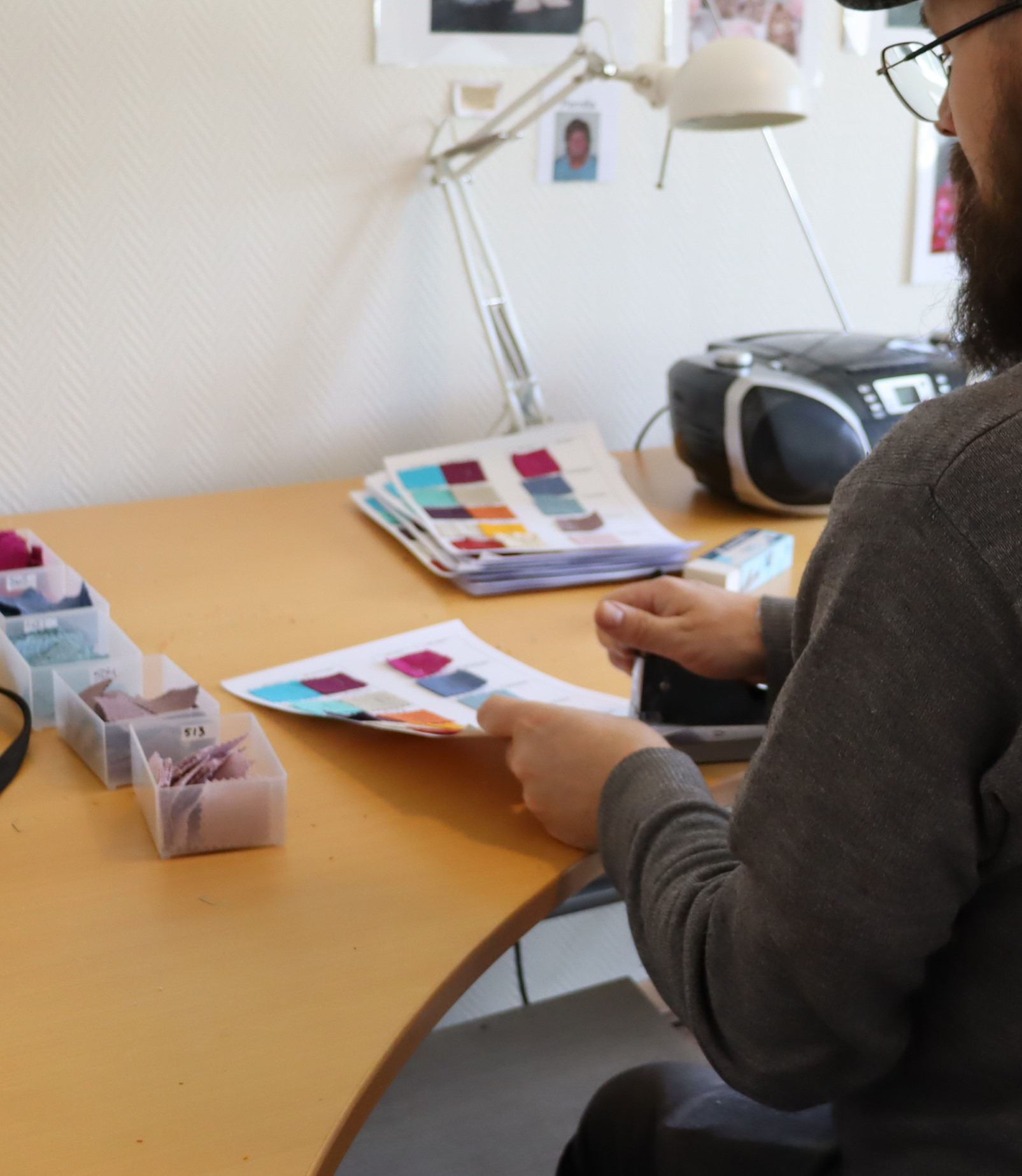 Bilden visar en person som arbetar med olika olika tygprover