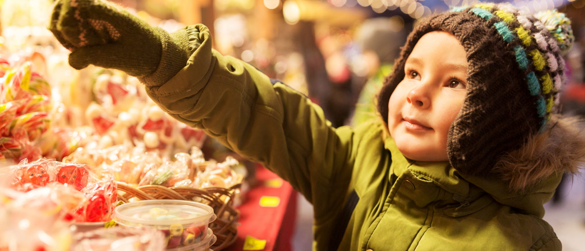 Foto: Marknadsstånd som säljer garn och hantverk, två kvinnor tiitar på varorna. I bakgrunden syns barn vid julgranen vid Hagatorget.
