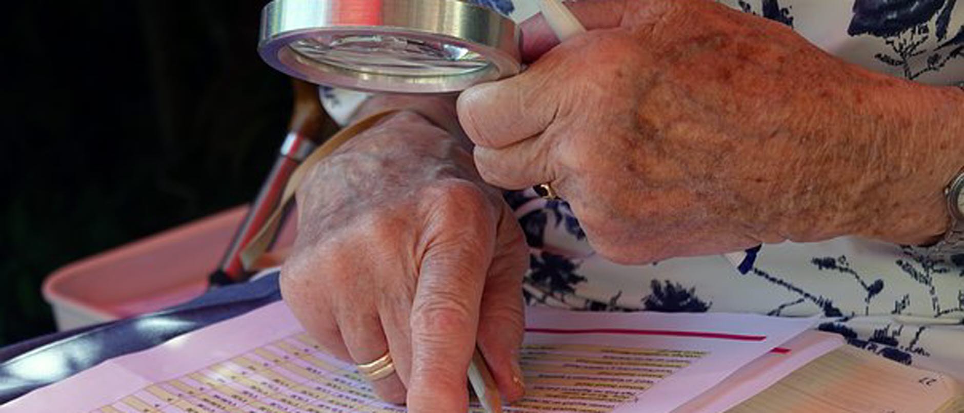 Bild på en äldre person som har ett förstoringsglas i handen